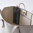Offene weiße Handtasche mit goldfarbenem Druckknopf und kleiner schwarzer Innentasche mit Reißverschluss.