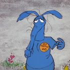 Ein blaues Tier mit langem Rüssel trägt ein Shirt mit der Aufschrift: "Help Stamp Out Ants".