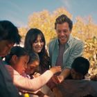 Es sind keine Texte im Bild. Eine Gruppe von Kindern und zwei Erwachsene lächeln gemeinsam im Freien bei sonnigem Wetter.