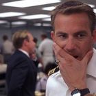 Ich kann keine spezifischen Texte identifizieren. Ein Mann in Marineuniform hält nachdenklich seine Hand ans Gesicht.