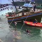 Text: "Nuclear Free Pacific", "Police", "Auckland Rescue". Ein sinkendes Schiff mit einem Regenbogenstreifen am Rumpf, Menschen im Wasser.