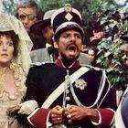 Eine Gruppe historisch gekleideter Menschen; eine erschrockene Frau, ein uniformierter Mann und weitere Personen im Hintergrund.