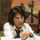 Ein Mann mit längeren Haaren in einem Fast-Food-Restaurant. Im Hintergrund eine orangefarbene Wanddeko mit Cowboy-Silhouetten.