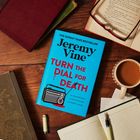 "Jeremy Vine, Turn the Dial for Death" in großen Lettern auf blauem Buch. Umgebung: Notizbuch, Stift, Tasse Tee, Brille.