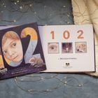 „102“ in großen Ziffern, darunter Augen und Tiere, by Matthew Cordell. Gemütliche Lichter auf einer Decke.