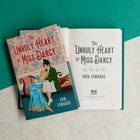 Buchtitel: "The Unruly Heart of Miss Darcy" von Erin Edwards. Ein Buch mit einer Illustration eines Paars auf einem Sofa.