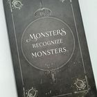"MONSTERS RECOGNIZE MONSTERS." Dunkler Hintergrund mit dekorativen Elementen und einem Schwertmotiv.