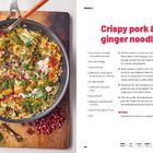 Texte: "Crispy pork & ginger noodles", Schritte und Zutatenliste rechts. Pfanne mit buntem Reisgericht links auf Holzbrett.