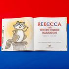 "Rebecca the White House Raccoon" steht in großen Buchstaben. Links ist eine Illustration eines fröhlichen Waschbären auf einer Säule.