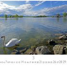"Frühlingstag am Bodensee", März-Kalenderblatt, zeigt einen Schwan im klaren Wasser nahe Felsen und grüner Küstenlinie.