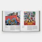 Links: M.CHAT. Rechts: HILARY PECIS. Links: ein Graffiti einer gelben Katze auf einem Gebäude. Rechts: ein gemaltes Bild einer Katze in einem Karton vor Bücherregalen.