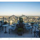 Seitenzahlen 168, 169 unten. Dachterrasse mit Stühlen, Tischen und Pflanzen, Aussicht auf Stadtlandschaft bei klarem Himmel.