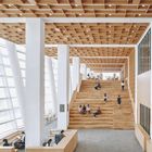 Ein Schild zeigt „F3“ und „C CLASS“. Moderne Bibliothek mit Holztäfelung, großen Treppen und Studierenden, die lesen und arbeiten.