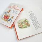 "Osterspaziergang: Die schönsten Gedichte und Geschichten" auf Buchcover. Illustration von Hasenfamilie. Geöffnetes Buch zeigt Text und Bild mit Hasen.