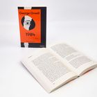 Ein Buchumschlag mit "George Orwell 1984" und ein aufgeschlagenes Buch. Dominierende Farben: Orange und Schwarz.