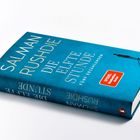 SALMAN RUSHDIE - DIE ELFTE STUNDE - FÜNF ERZÄHLUNGEN. Blauer Buchumschlag mit kleiner Figur und rotem Aufkleber.