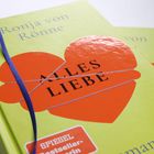 "ALLES LIEBE" steht auf einem roten Herz, im Buchcover-Design. Darunter ein Abzeichen: "SPIEGEL Bestseller-Autorin".