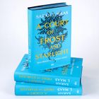 Ein Stapel Bücher mit blauem Einband, Titel: "A Court of Frost and Starlight". Autor: Sarah J. Maas.