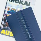 YAEL INOKAI DIE AUSTER auf einem blauen Buchrücken; darunter ein Buch mit teils sichtbarer farbiger, urbaner Illustration.