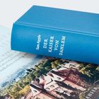 Buchtitel "Der Kaiser von Dahlem" von Sam Apple. Ein blaues Buch liegt auf einer Zeitschrift mit Stadtfoto.