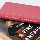 Zwei Bücher, beide mit dem Titel „Ach, eine Fanfare!“ von Elke Heidenreich, eines zeigt ein Porträt einer Frau.