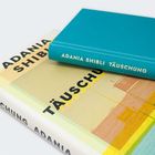Zwei Bücher mit dem Titel „Täuschung“ von Adania Shibli. Eines hat einen türkisfarbenen Umschlag.