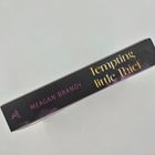 "Tempting little Thief" in goldener Schrift, "MEAGAN BRANDY" in Pink auf schwarzem Hintergrund.