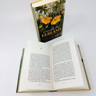 Auf dem Buchcover steht „Claudia Rikl - Elbland - Roman“. Das Cover zeigt gelbe Blüten. Ein Buch liegt aufgeschlagen daneben.