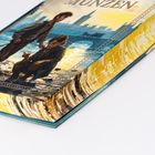 Oben rechts steht "MÜNZEN". Zwei Jungen, der eine stehend, der andere hockend, am Flussufer mit Stadt im Hintergrund.