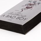 Text: "Roman", "Tricking a Bad Boy", "Cove". Ein Buch mit grauem Einband und floralem Design.