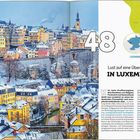 "Lust auf eine Überraschung in Luxemburg?" Große "48" daneben. Schneebedeckte Stadtansicht mit bunten Gebäuden und Karte oben.