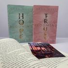 Vorne eine Buchseite, darauf ein Bild. Dahinter zwei Bücher: „HOPE BLOOMING“ in Mintgrün und „TRUST BLOOMING“ in Rosa.