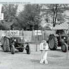 LANZ KRAFTGESPANN / BULLDOG-REIHE HL 1912–1927. Zwei Traktoren, Zelte, Schilder im Freien.