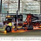 "Erstklassiger Service" auf Lastwagen und Anhänger. Im Hintergrund ein modernes Gebäude. Ein Kalender zeigt September.