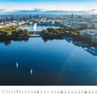 „April“ und Kalendertage. Gebäude mit wellenförmigem Dach ragt aus Nebel, im Hintergrund Kräne und Windkraftanlagen.