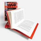 Der Text auf dem Buchcover lautet: "WUT & WÄRME". Das Buch ist geöffnet, rote Akzente sind sichtbar.