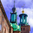 Ein altes Gebäude mit grünen Kuppeln und Türmen, verziert mit goldenen Sternen, gegen einen blauen Himmel.