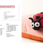 "Mona Marienkäfer, spielt gerne Bingo." Anleitung für eine gehäkelte Marienkäferfigur, liegend auf einem orangefarbenen Kissen.