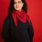 Ich kann keine erkennbaren Texte oder Logos sehen. Eine Frau trägt einen roten Schal vor rotem Hintergrund.