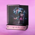 Eine Illustration in einem Buch zeigt ein stilvolles Paar in einem Auto. Auf dem Buchrücken Symbole wie Kreuze und Monde.