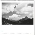 "Juni" steht unten links. Darunter sind Kalendertage. Oben Schwarz-Weiß-Foto von Bergen mit Wolken am Himmel.