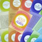 Ein Buch mit dem Titel "Erwecke die Kraft deiner Aura" umgeben von farbigen Karten mit spirituellen Botschaften.