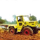 Ein großer, hellgrüner Traktor pflügt ein Feld, im Hintergrund sind Bäume sichtbar.