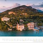 März-Kalender mit Bild einer idyllischen Küstenlandschaft, Häuser, Bäume, und ein Bootssteg im Hintergrund.