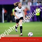 © DFB – Vorjahresabbildung. Eine Fußballspielerin in Aktion, läuft mit einem Ball. Kalendarium am unteren Rand.