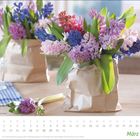 Kalenderblatt: Tage und Termine im März. Ein braunes Papiertütchen voller bunter Hyazinthen auf einem Tisch.