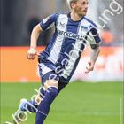 Text: "Dawid Kownacki", "CHECKCARS24", "Hertha BSC". Ein Fußballspieler in Aktion, trägt ein blau-weißes Trikot.