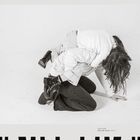 „UNTITLED, From the series: NILA“. Zwei Personen in Overalls, eine kniet, die andere sitzt auf ihrem Rücken.