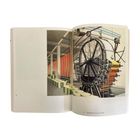 Seite 43, Papeirmaschne Papermachine 1934. Illustration einer Fabrik mit großen Maschinenrädern und Papierrollen.