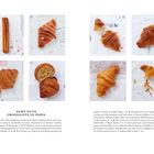 Acht gute Croissants in Paris. Beschreibungen von acht verschiedenen Croissants, teilweise angebissen, auf Papier liegend.